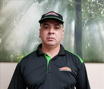 Male Employee wearing black SERVPRO top Green trim and SERVPRO Logo and Black hat with Green trim with SERVPRO logo 